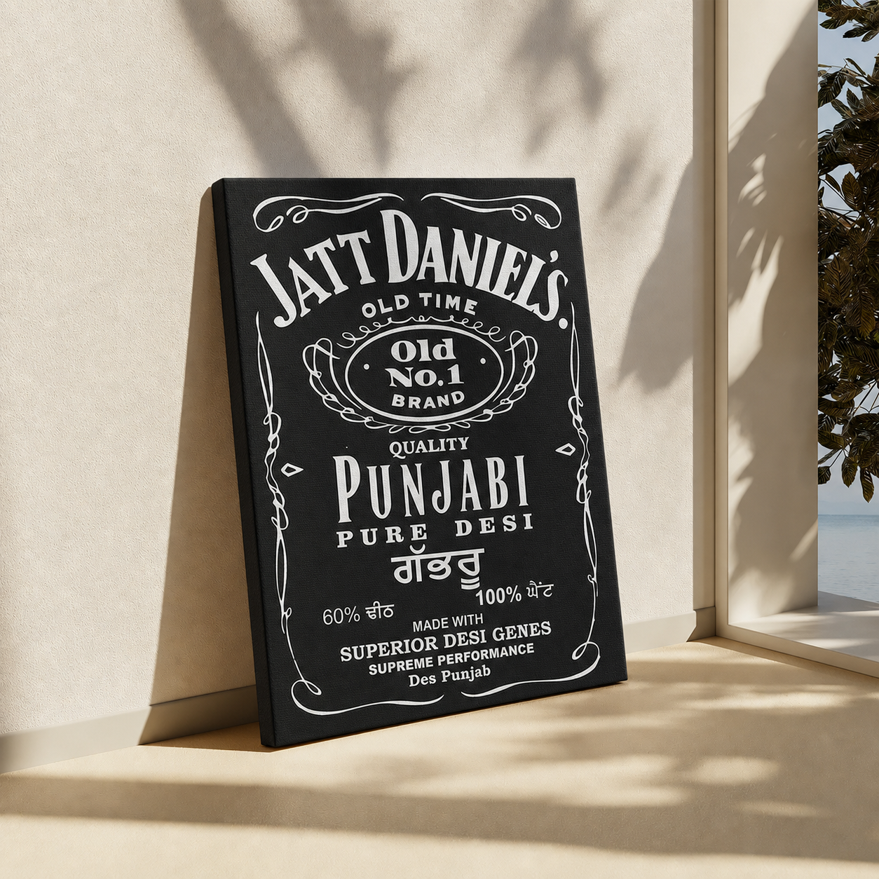 A black rectangular wall art print or sign with white vintage-style text reading 'Jatt Daniel's' and 'Punjabi Pure Desi,' leaning against a beige wall in a sunlit interior near a window.