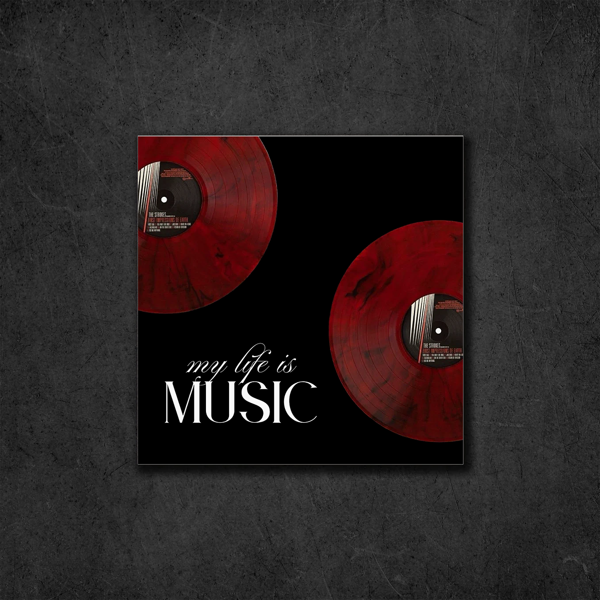 A square wall art print or poster featuring two red vinyl records on a black background with the text 'my life is MUSIC' in white, displayed against a dark textured wall.