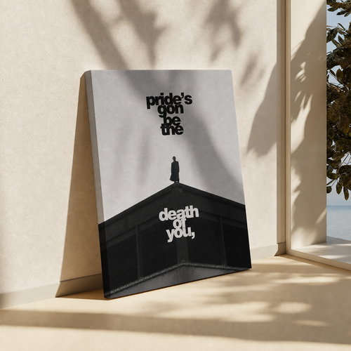 A square art print or poster leaning against a beige wall on a windowsill, with sunlight and leaf shadows cast across it. The print shows a black-and-white architectural scene with the text 'pride's gonna be me' in black and 'death of you,' in white.