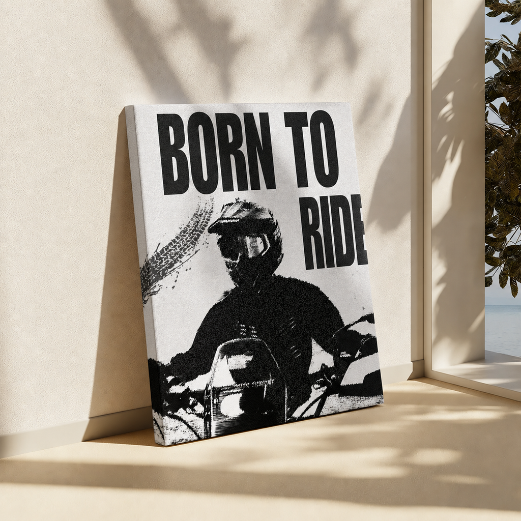 A rectangular wall art print or canvas leaning against a beige wall in a sunlit interior. The artwork shows a black-and-white motorcycle rider with large bold text reading “BORN TO RIDE.