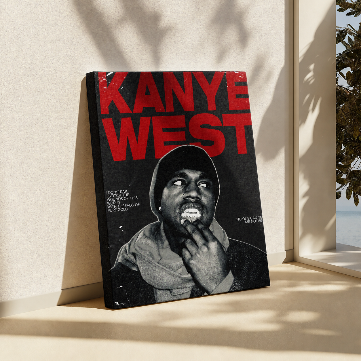 A canvas print leaning against a beige wall on a windowsill, featuring a black and white portrait of Kanye West with bold red text reading 'KANYE WEST'.