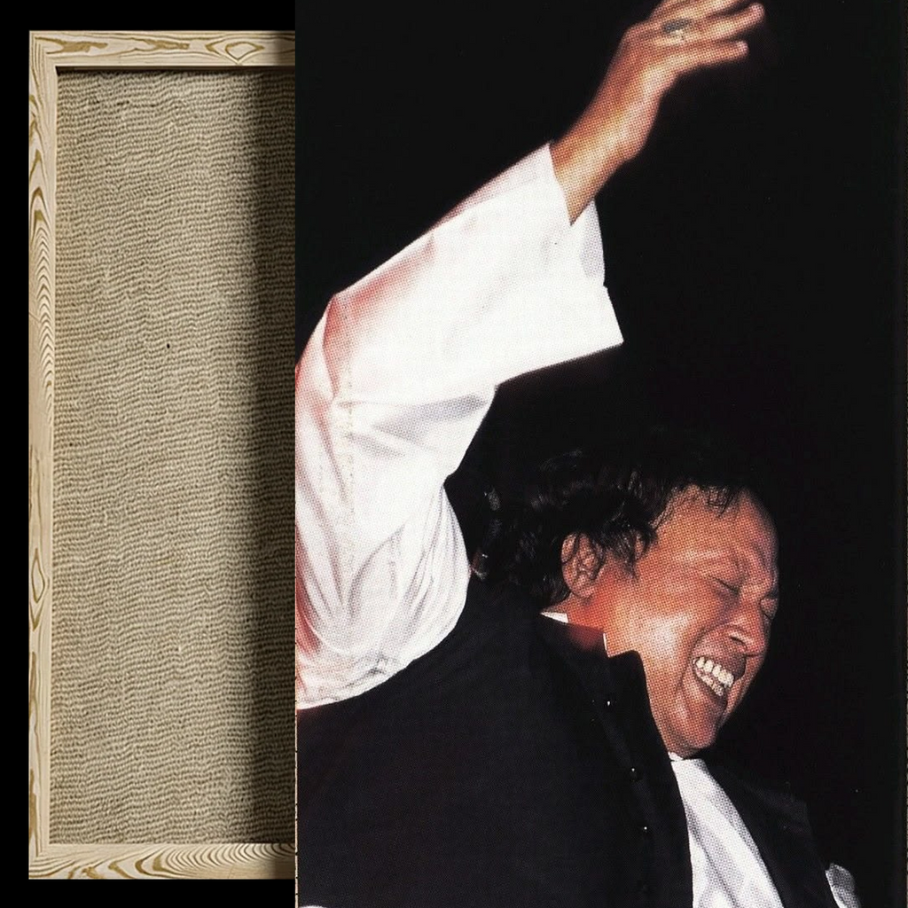 A framed art print or photograph shown against a black background, featuring a smiling man in a white shirt and dark jacket with one arm raised. The left side of the frame also shows a close-up of a textured beige woven or wood-like panel within a light wood frame.
