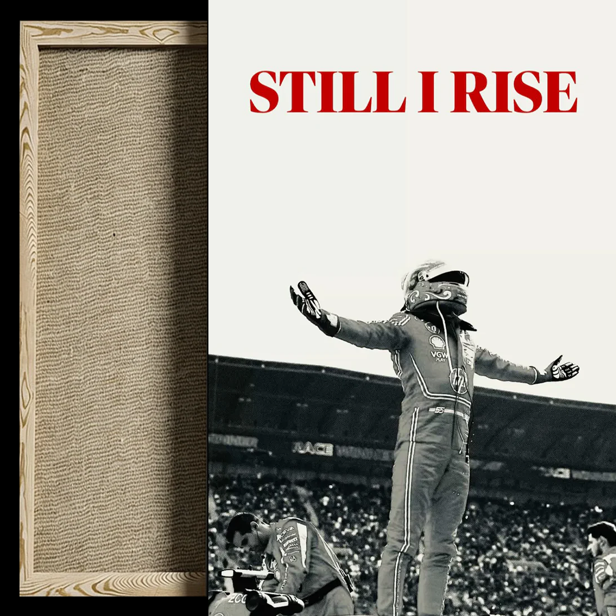 A framed wall art print featuring a black-and-white photograph of a race car driver celebrating on a track, with the red text 'STILL I RISE' at the top. A narrow wood frame border is visible on the left against a dark background.