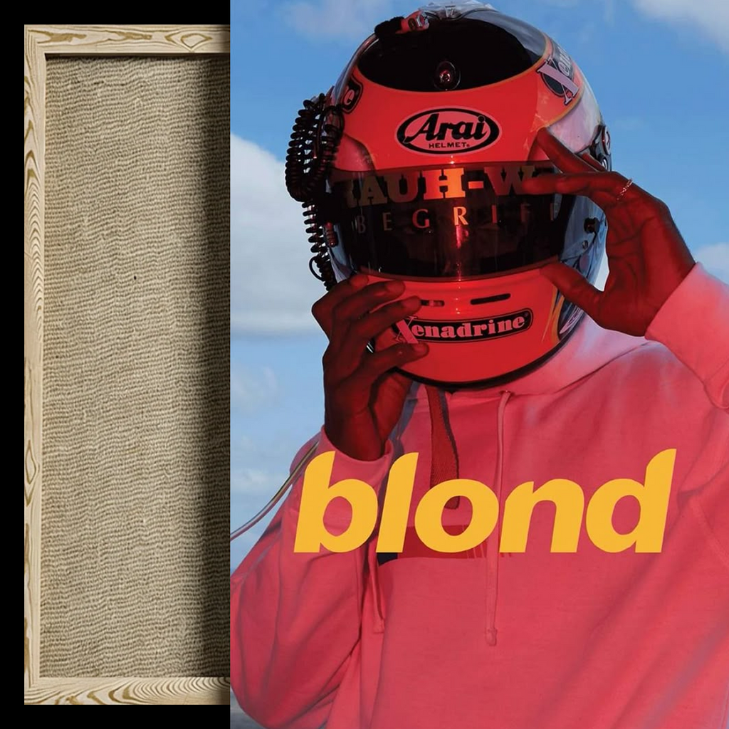 A framed art print featuring a stylized portrait of a person in a pink hoodie and red racing helmet against a blue sky, with the word 'blond' in large yellow text. A blank textured beige square is shown on the left as a color/material swatch preview.