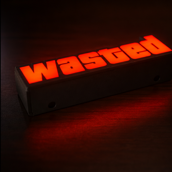 A rectangular black sign with the word 'Wasted' in large glowing red letters, photographed on a dark surface with red light reflecting below.