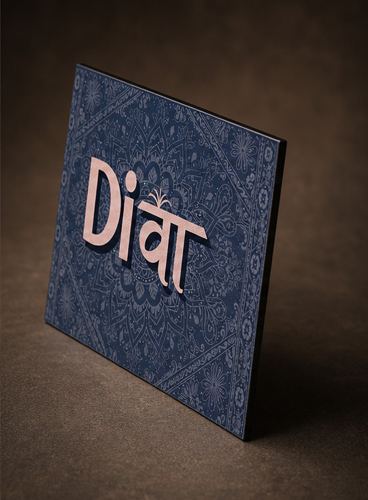 A square navy blue decorative card or plaque with an ornate floral pattern and the word 'Diwa' in large metallic pink letters, photographed on a dark brown textured surface.