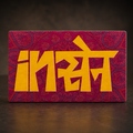 A rectangular decorative canvas print featuring the word 'Insane' in bold yellow letters over a textured magenta and purple patterned background, displayed on a dark wooden surface.
